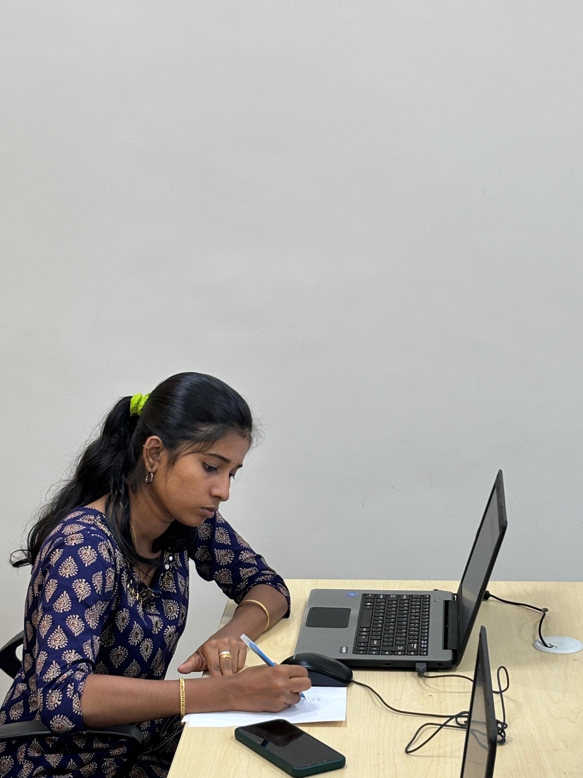 A Learning Pod tutor at work, focused on paperwork beside a laptop