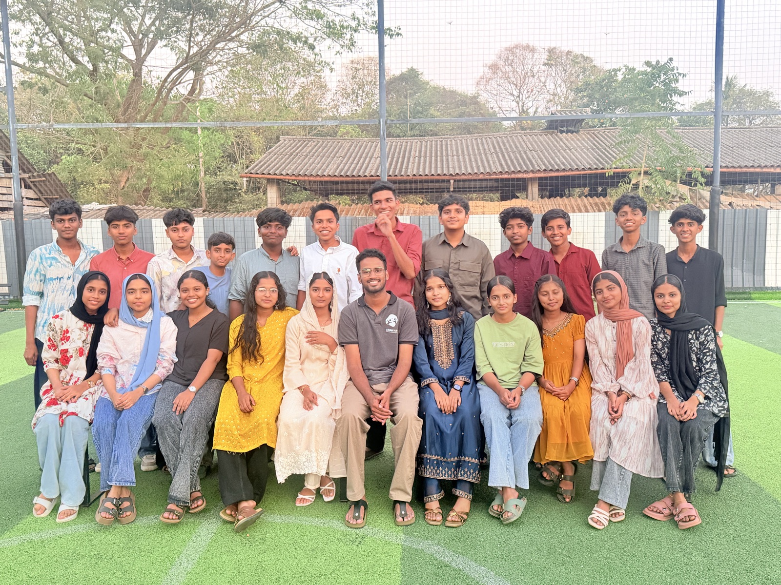 A large group photo of Learning Pod students together on the turf ground